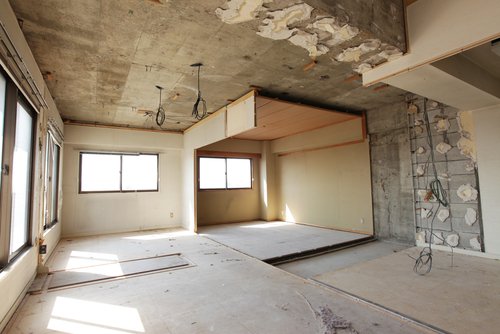 Woman painting a wall cyan color with a roller in a house